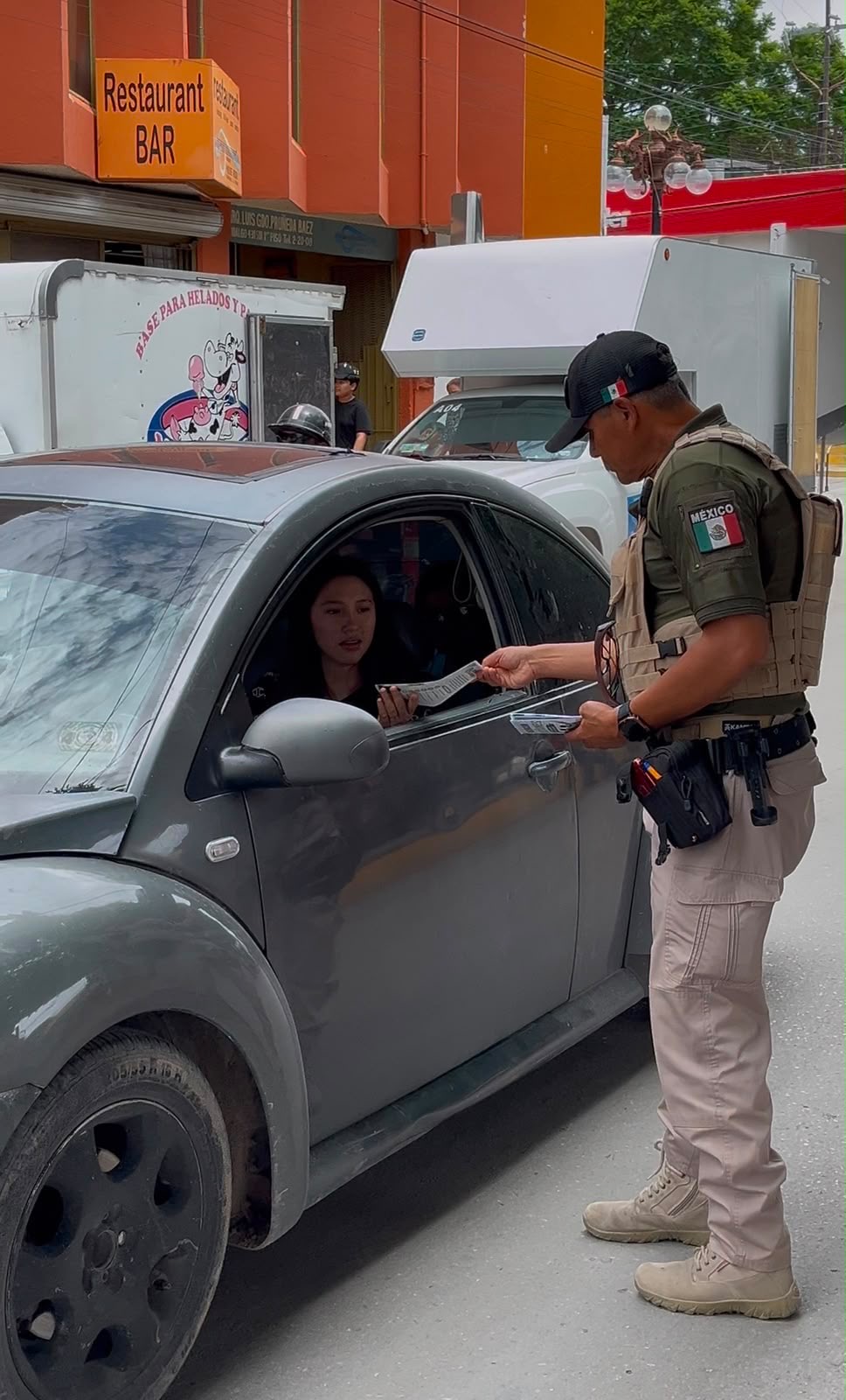 Elemento de la Guardia Civil Estatal entrega material informativo a una automovilista durante una jornada preventiva en Matehuala.