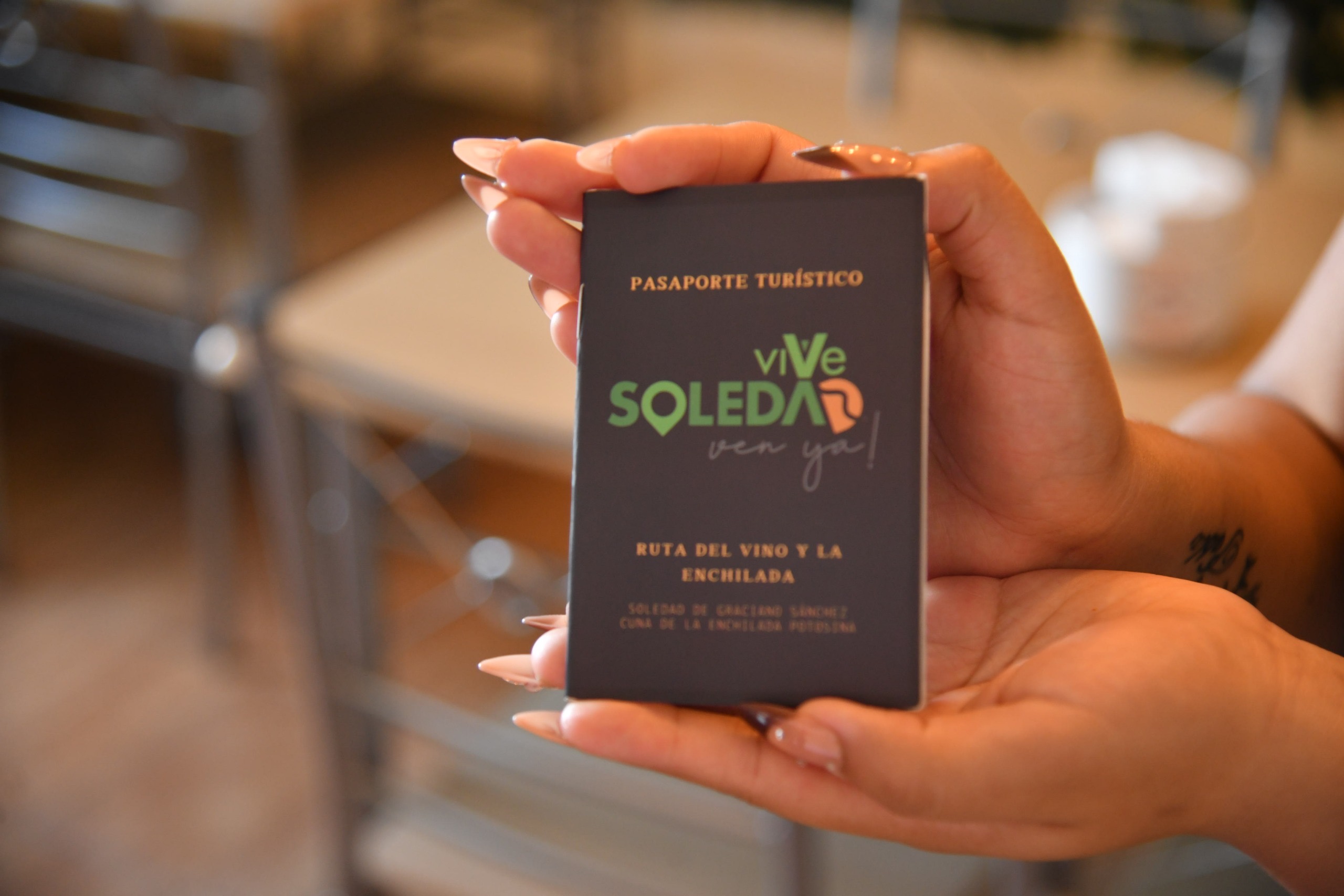 Persona sostiene el Pasaporte Turístico Vive Soledad, parte de la Ruta del Vino y la Enchilada en Soledad de Graciano Sánchez.