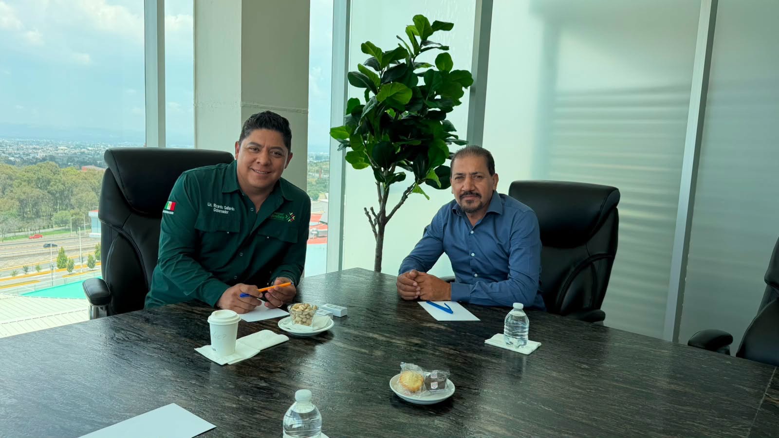Dos funcionarios reunidos en una sala de juntas durante el anuncio de obras y apoyos para Villa de Guadalupe.