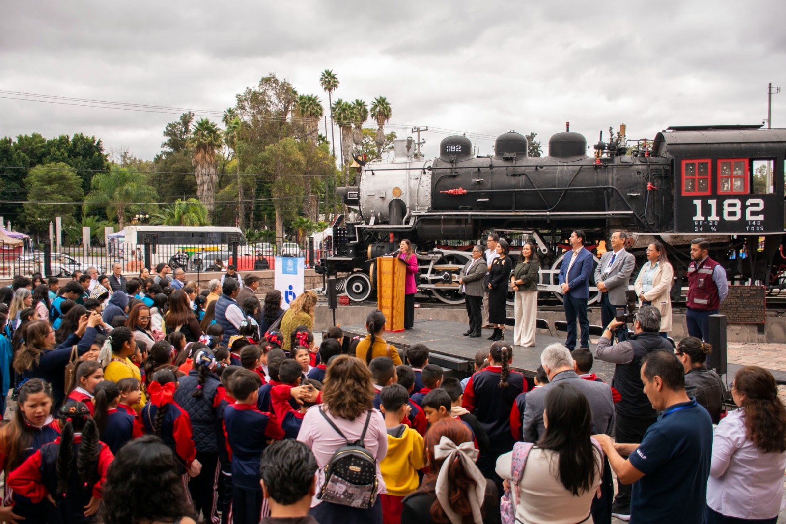 Asistentes y estudiantes participan en la inauguración del festival El agua nos mueve de la UASLP, junto a la locomotora 1182 en el Museo del Ferrocarril Jesús García Corona.