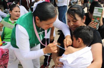 Personal de salud aplica una vacuna a un menor acompañado por una adulta durante una jornada de vacunación.