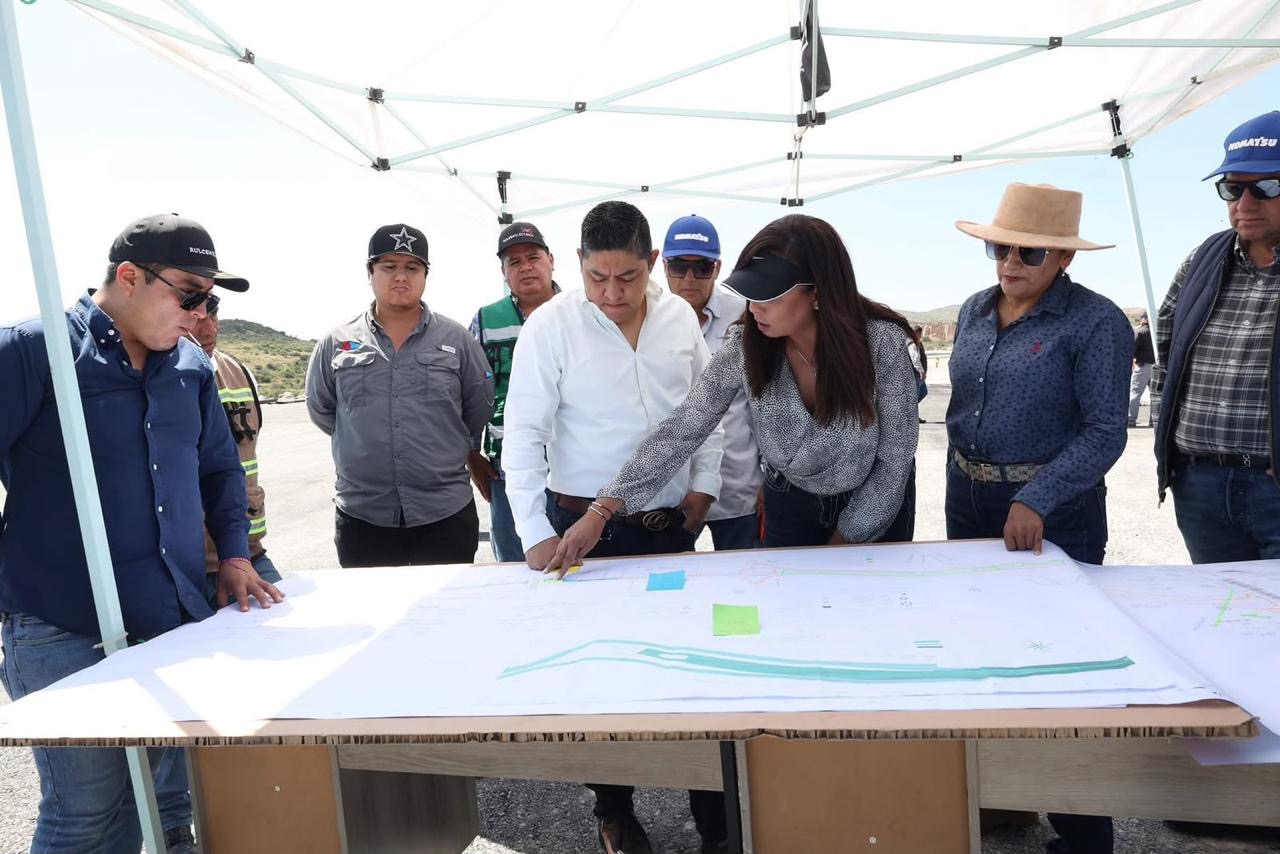 Autoridades estatales y personal técnico revisan planos de un proyecto de infraestructura bajo una carpa