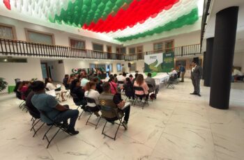 Funcionarios y asistentes participan en reunión sobre la Guía Consultiva de Desempeño Municipal en un patio institucional decorado con motivos tricolores.